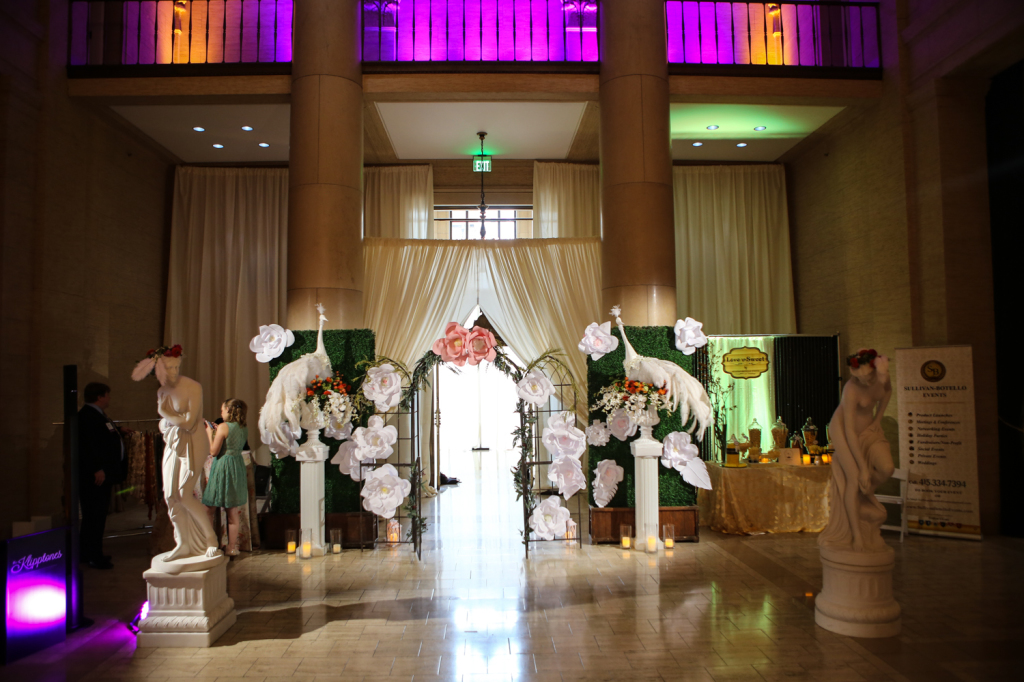 Wedding decorum of flower installations and statues underneath multicolored up-lighting
