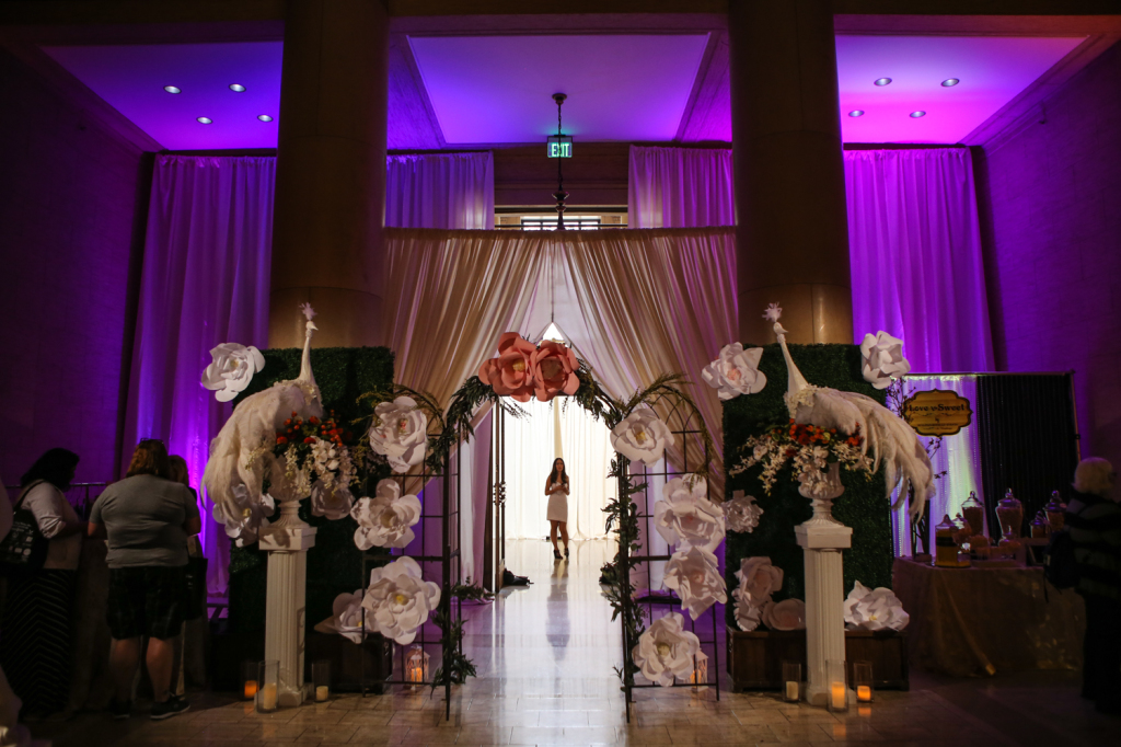 Venue decorum of flower installations and statues with purple up-lighting and drapery