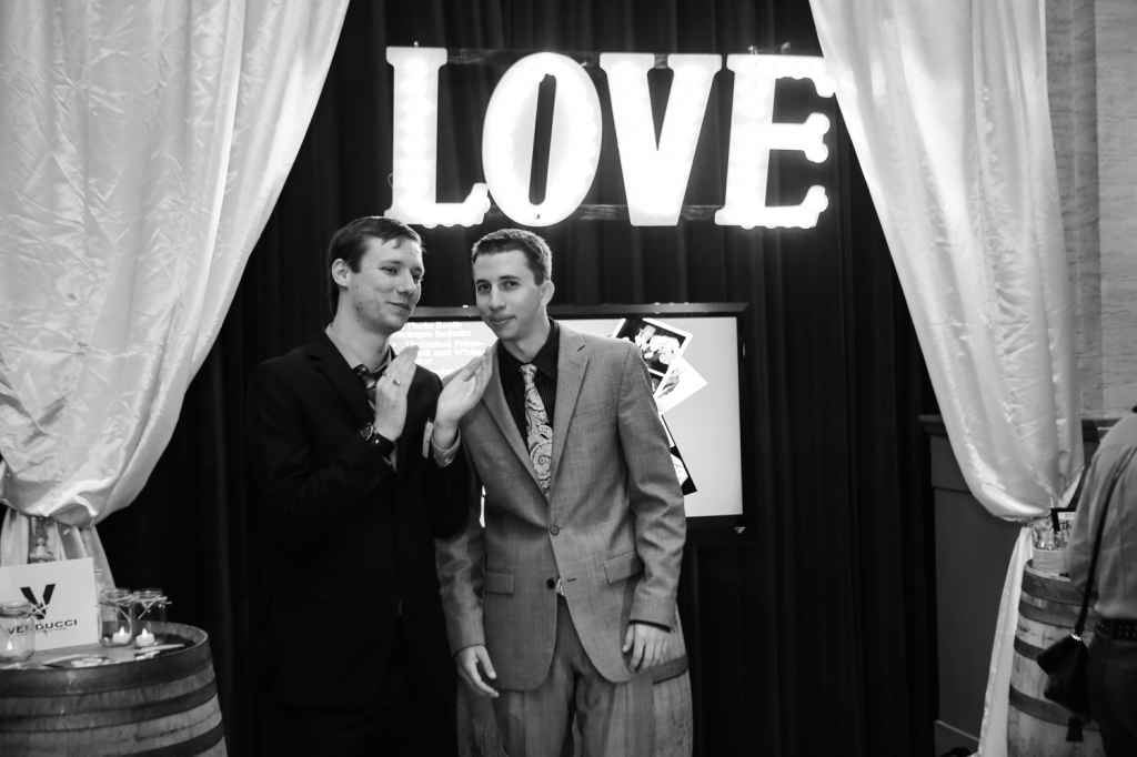 two men posing in front of LOVE light signage and drapery installation